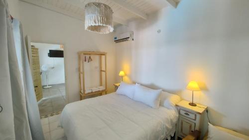 a white bedroom with a bed and a bathroom at El Nopal - Alojamiento in San Pedro