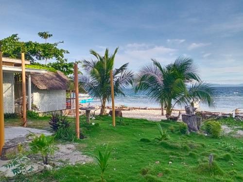 a house on the beach with palm trees and the ocean at Nitasnipahut Pamilacan island in Pamilacan