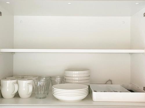 a kitchen with white plates and bowls on a shelf at PRISM Inn Komagata Asakusa in Tokyo