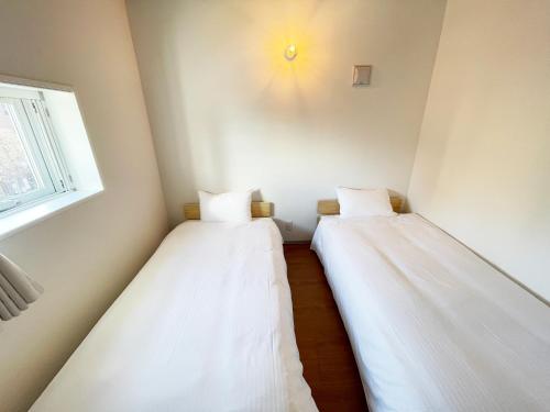 two beds in a small room with a window at PRISM Inn Komagata Asakusa in Tokyo