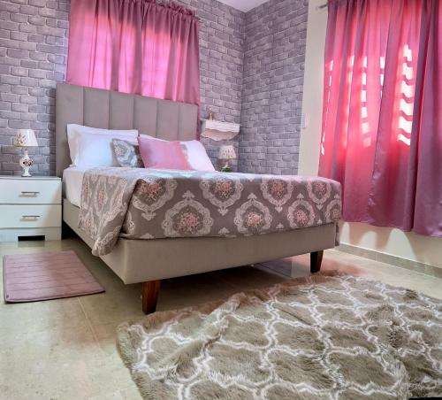 een slaapkamer met een bed met roze gordijnen en een tapijt bij A-1 Hermoso Apartamento tipo villa al pie de la montaña elitevillasjarabacoa in Jarabacoa