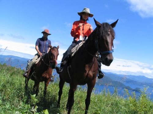 two people riding horses on a grassy hill at Yutorelo Toyako in Lake Toya