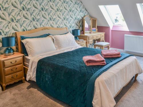 a bedroom with a bed with a blue blanket and a mirror at Quarrymans Cottage in Belford