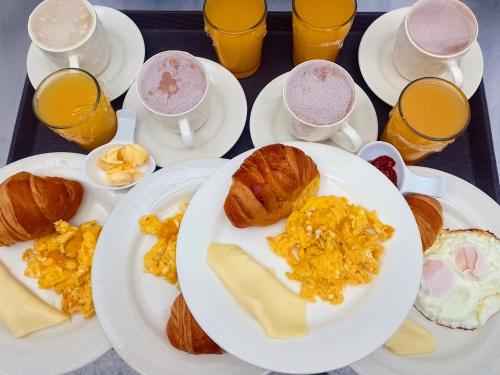 a table with plates of breakfast foods and glasses of orange juice at Apartamentos Casa MJ Tunja in Tunja