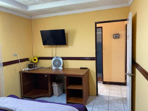 a room with a desk with a television on a wall at Casa Lupita Alajuela in Alajuela