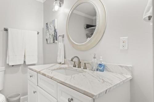 ein weißes Badezimmer mit einem Waschbecken und einem Spiegel in der Unterkunft Palmetto House of Charleston in Charleston