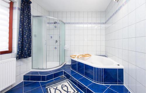 a blue tiled bathroom with a tub and a shower at Nice Home In Velika With Outdoor Swimming Pool in Velika