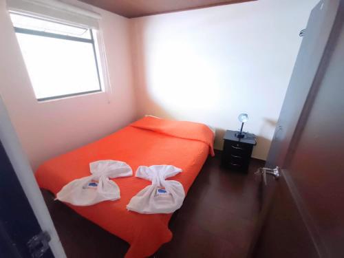 a small bedroom with an orange bed with towels on it at Apartamentos CasaMJ Tunja Confort y Parqueadero in Tunja