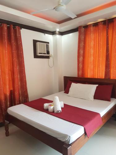 a bedroom with a bed with orange curtains at JACE'S Travelers Inn in El Nido