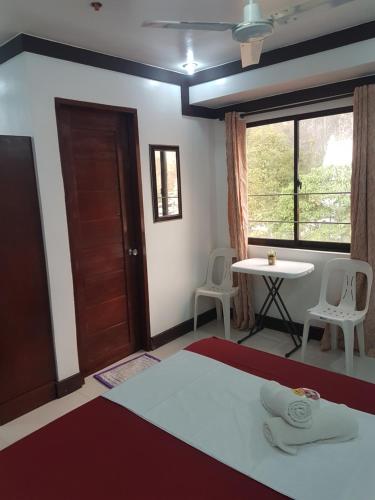 a room with a bed and a table and a window at JACE'S Travelers Inn in El Nido