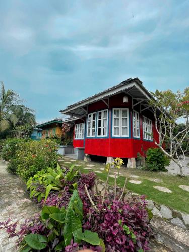 a red and black house with flowers in front of it at Rock and Wreck Dive Resort in Tanjungbinga