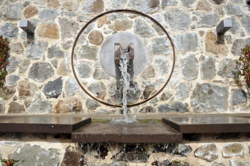 a water fountain in front of a stone wall at Hotel Maison Tresnuraghes in Tresnuraghes