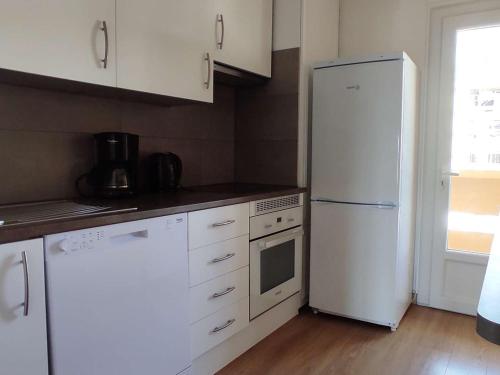 Il comprend une cuisine équipée d'appareils électroménagers blancs et d'un réfrigérateur blanc. dans l'établissement Appartement cosy 3 pièces, 6 pers, proche centre Font-Romeu, télécabines, avec parking et balcon - FR-1-580-85, à Font-Romeu-Odeillo-Via