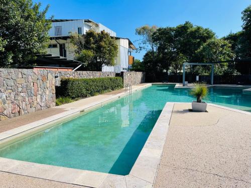 a swimming pool with blue water in front of a building at Cosy Apartment at Sebel Twin Waters Resort w Private Garden - 2 Mins Walk to Beach & River in Mudjimba