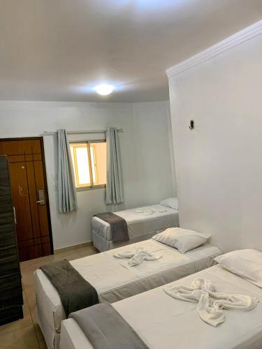 a room with three beds in it with a window at Hotel Diamante Negro in Salvador