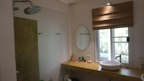 La salle de bains est pourvue d'un lavabo, d'un miroir et d'une fenêtre. dans l'établissement Baan Zourite seaview villa, à Ko Mak