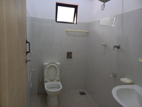 een badkamer met een toilet, een wastafel en een raam bij Sayura Guest House in Trincomalee