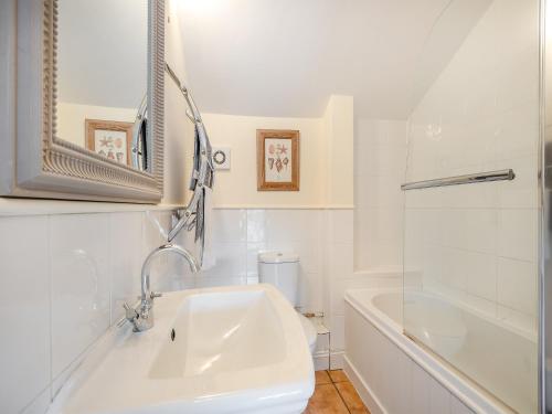 ein weißes Badezimmer mit einem Waschbecken und einer Badewanne in der Unterkunft Norfolk Cottages - The Ostlery in Smallburgh