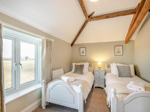 2 Betten in einem Zimmer mit Fenster in der Unterkunft Norfolk Cottages - The Ostlery in Smallburgh