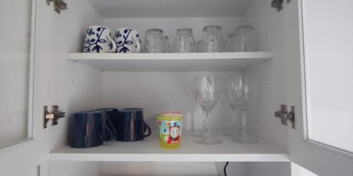 a white cabinet with glasses and wine glasses at They are NOT HOUSE - Vacation STAY 86998 in Okinawa City