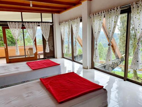 two beds in a room with large windows at Argapuri Jungle Resort Ciwidey in Ciwidey