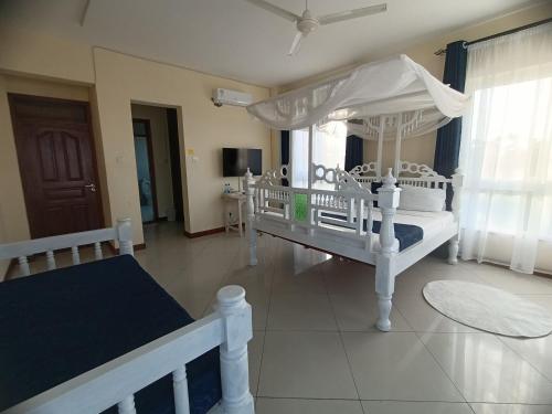 a bedroom with two white beds and a canopy at Elna's Nyali - Seaview, Pool, High Speed Wi-Fi & Hot Shower in Mombasa