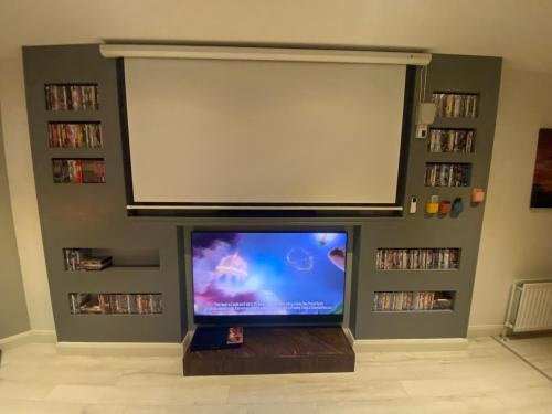 TV de pantalla plana en la sala de estar con una pantalla grande en Sleeps 18 Double Decker Bus Hot Tub Sauna Cinema Pets, en Irvinestown