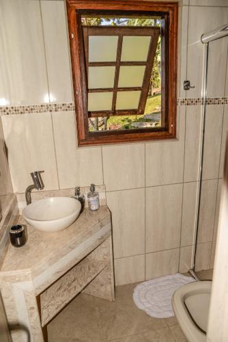 a bathroom with a sink and a mirror at Chalés Araucária e Manacá in São Bento do Sapucaí