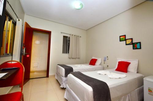 a hotel room with two beds and a red chair at Hotel Diamante Negro in Salvador