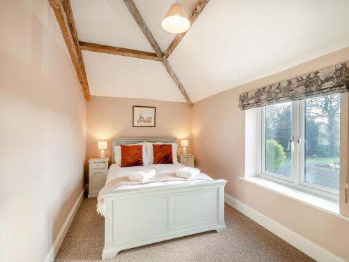 a bedroom with a white bed and a window at Norfolk Cottages - The Coach House in Smallburgh