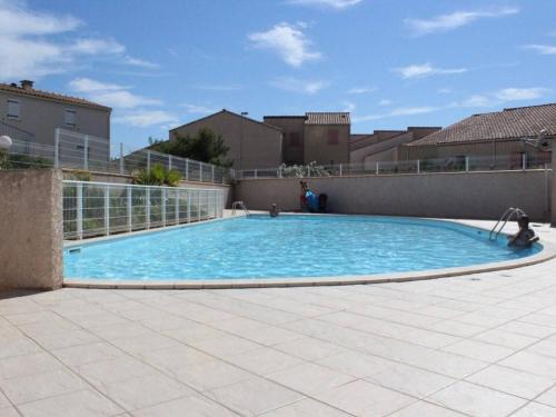 une grande piscine d'eau bleue dans une cour dans l'établissement Charmant 2 pièces avec mezzanine, terrasse et piscine - Saint-Pierre-la-Mer, 6 couchages - FR-1-229D-354, à Saint Pierre La Mer