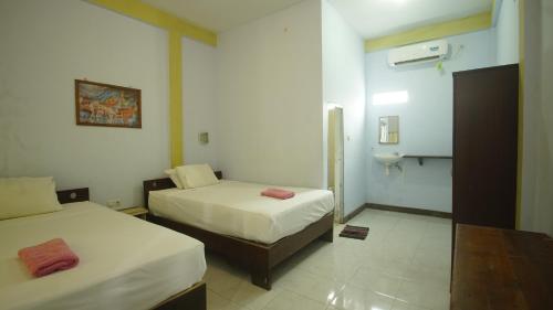 a room with two beds and a sink in it at mimi kuta homestay in Kuta Lombok