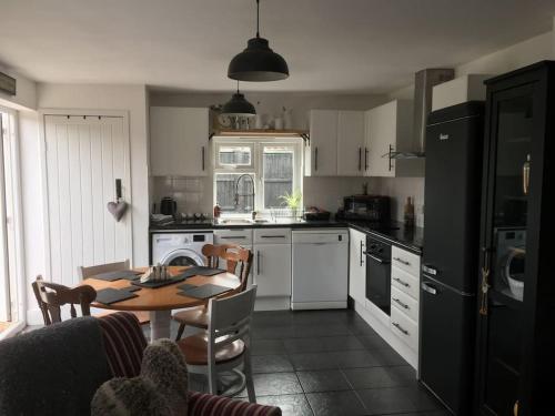 a kitchen with a table and a kitchen with white cabinets at Herb Garden Bungalow in Nazeing