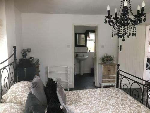 a bedroom with a bed and a chandelier at Herb Garden Bungalow in Nazeing