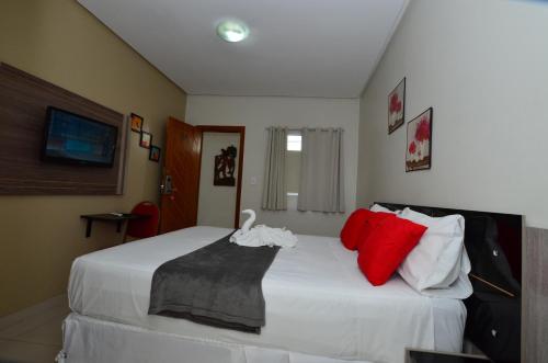 a bedroom with a large white bed with red pillows at Hotel Diamante Negro in Salvador