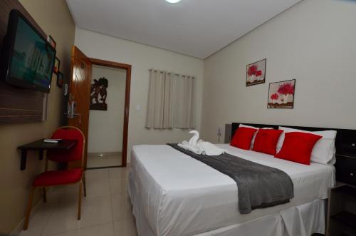 a bedroom with a bed with red pillows and a television at Hotel Diamante Negro in Salvador