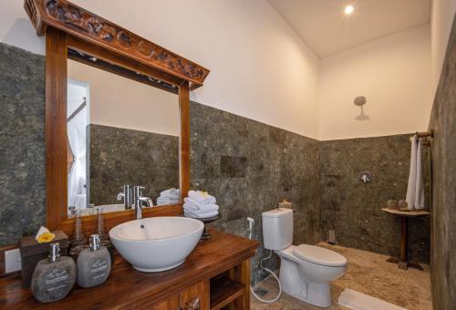 a bathroom with a sink and a toilet at Swan Paradise A Pramana Experience in Gianyar