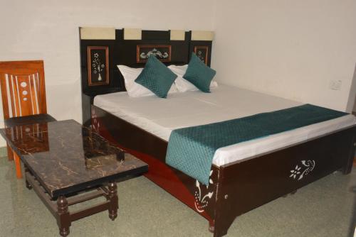 a bedroom with a bed with a chair and a table at Hotel Holiday in Bharatpur