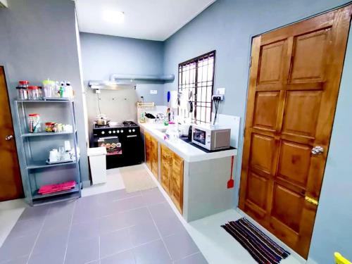 a small kitchen with a stove and a refrigerator at Izzara Iskandar Puteri Homestay Gelang Patah in Gelang Patah