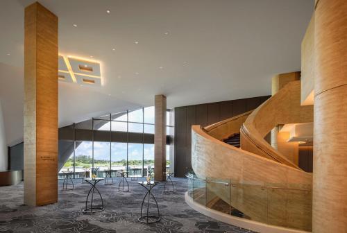 a lobby with a wooden spiral staircase and chairs at Dusit Thani Laguna Singapore in Singapore