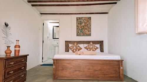 1 dormitorio con cama y tocador de madera en Welikande Yoga Retreats en Digana
