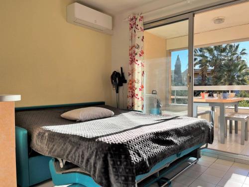 une chambre avec un lit et une grande fenêtre dans l'établissement Studio cabine 4 pers avec terrasse, clim et parking au Lavandou - FR-1-251-431, au Lavandou