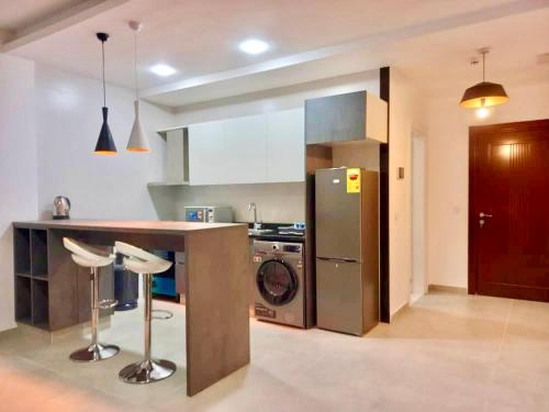 a kitchen with a refrigerator and a counter with stools at Harmony Park, East Cantonments, Accra in Accra