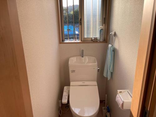 a small bathroom with a toilet and a window at 一日一組の宿ひめ in Kushimoto