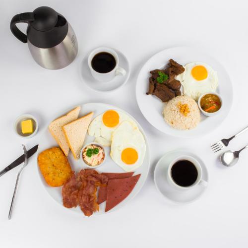 a white table topped with plates of breakfast food at AMALFI718 HOTEL in Lipa