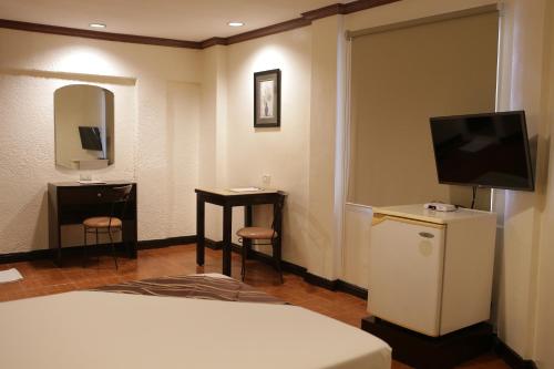 a hotel room with a bed and a television and a table at AMALFI718 HOTEL in Lipa