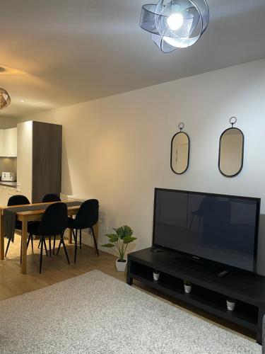 a living room with a television and a table with chairs at Great 1Bed 10 mins from East Croydon with Free WiFi in Croydon