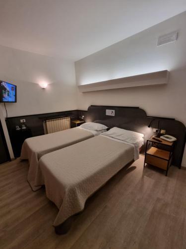 a hotel room with two beds and a tv at CityHotel Cristina Vicenza in Vicenza