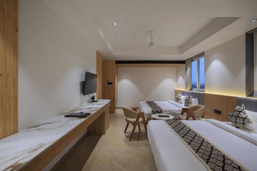 a hotel room with two beds and a desk at Hotel Aditya Mansingh Inn in Somnath