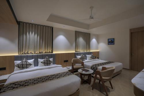 a hotel room with three beds and a table at Hotel Aditya Mansingh Inn in Somnath